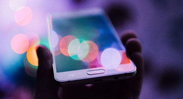 hand holding a smartphone with brightly colored lights blocking the view of the screen
